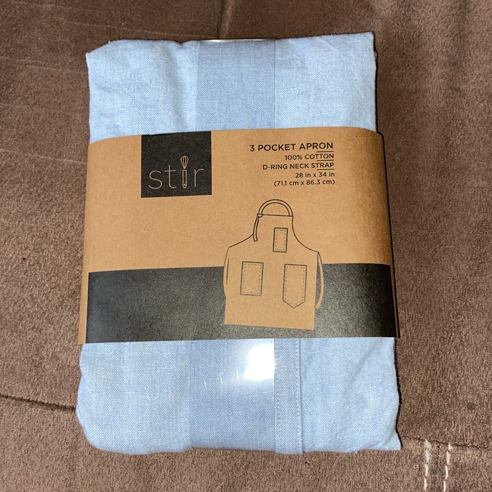 “Stir” light denim colored cotton apron. Adult one size fits most.